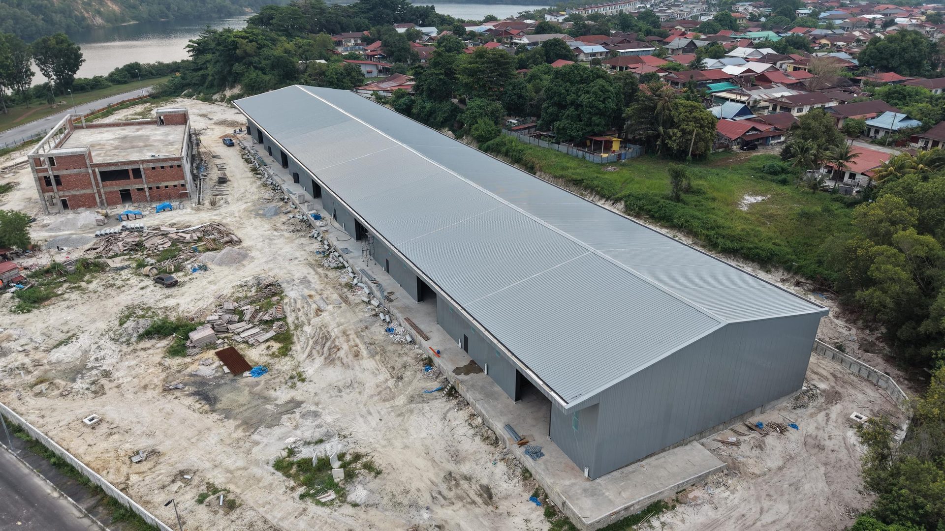 Aerial view of the completed warehouse roof beside the lake and village
